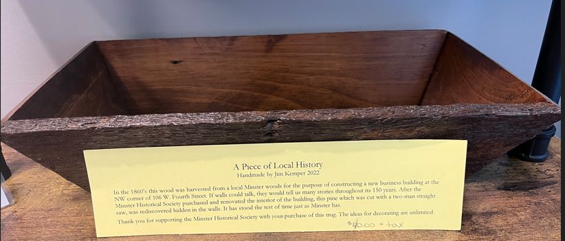 Wooden carved tray on a shelf with a yellow museum label in front