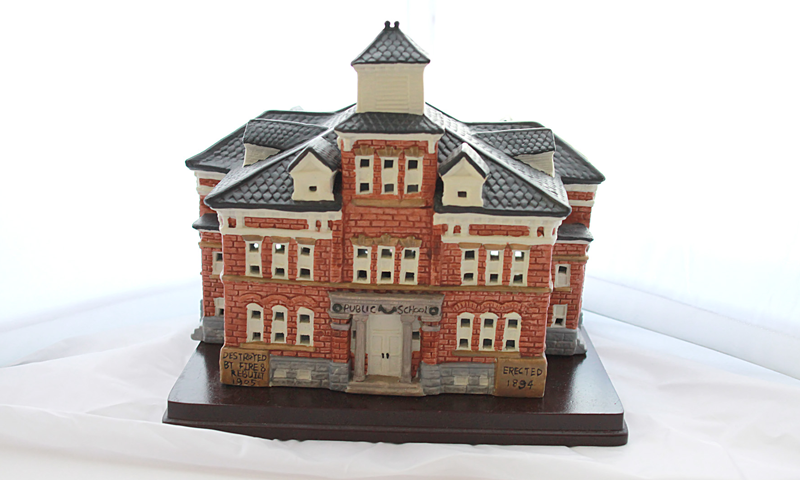 Detailed model of a red-brick Victorian-style building on a base, with a central tower and gray roof.