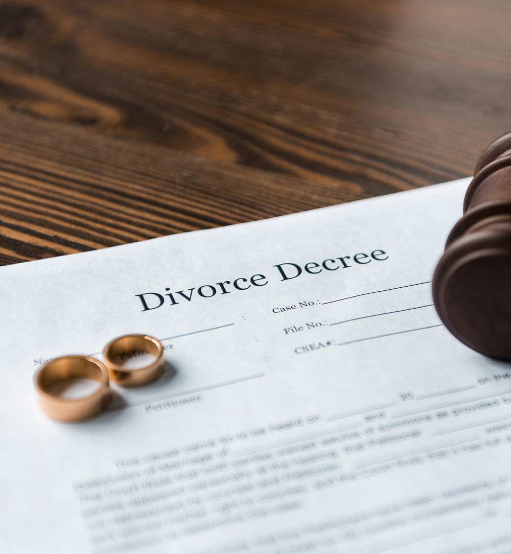 Divorce decree document with wedding rings and a gavel on a wooden table.