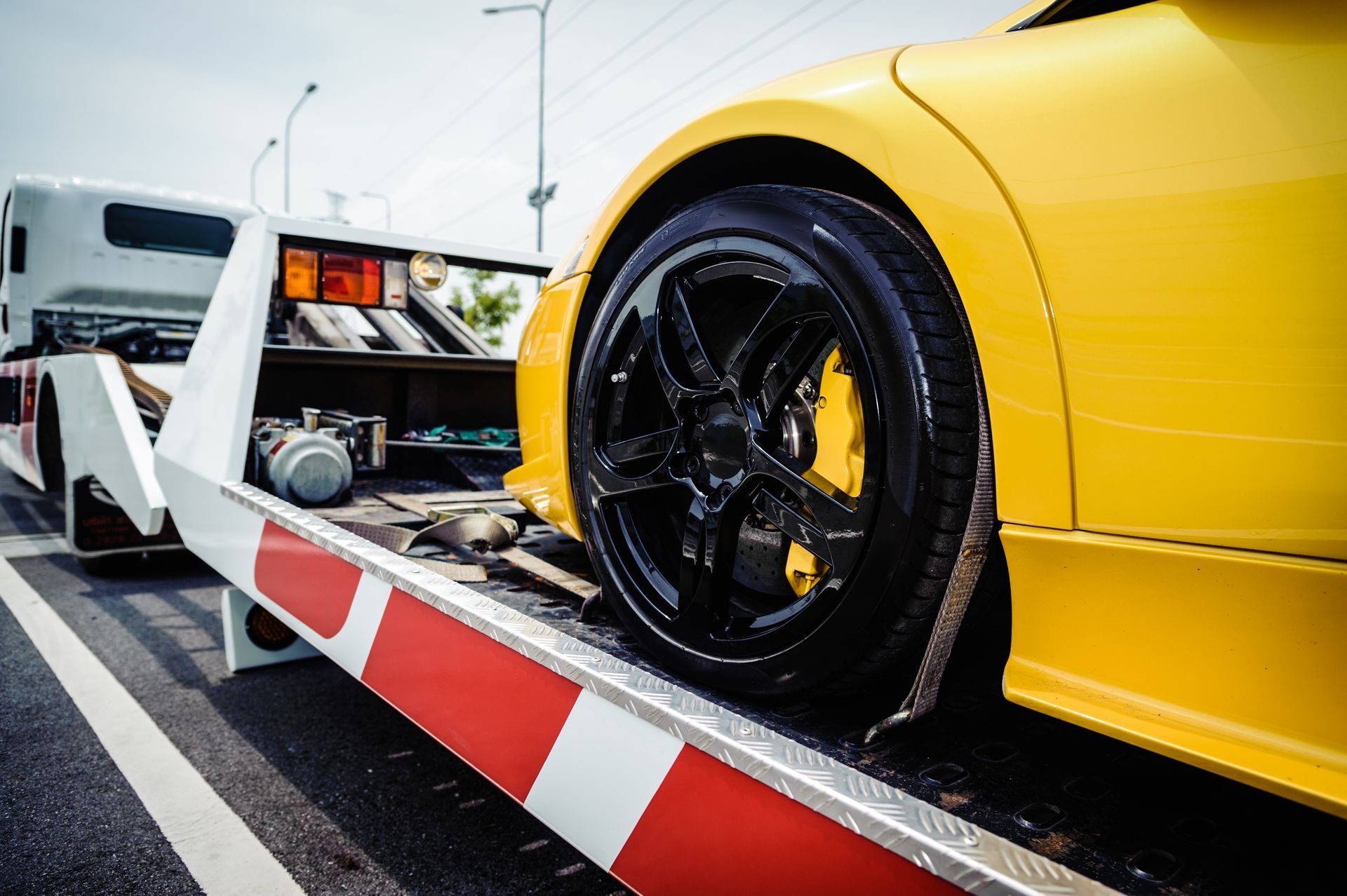 A flatbed tow truck is loading a broken vehicle for long-distance towing. A flatbed tow truck is loading a broken vehicle for long-distance towing.