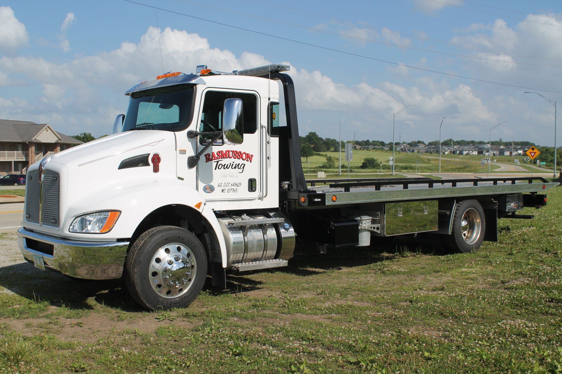 A white tow truck is parked in a grassy field