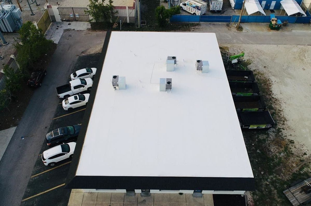 An aerial view of a white roof with cars parked on it.