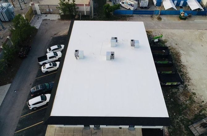 An aerial view of a white roof with cars parked on it.