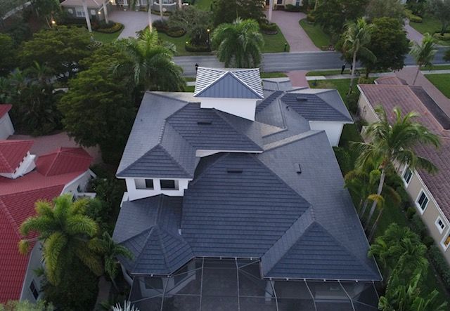 An aerial view of a large house with a gray roof in a residential area.