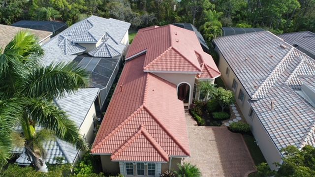 An aerial view of a house with a red tile roof surrounded by other houses.