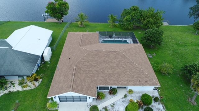 An aerial view of a house with a pool and a lake in the background.