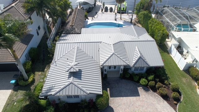 An aerial view of a house with a gray roof and a pool.