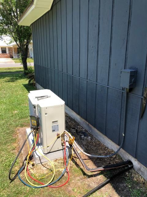 An industrial HVAC unit with two pleated filters sits inside a utility closet with light-colored walls and carpet.