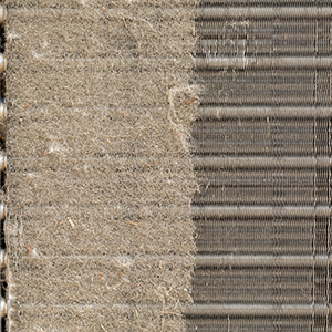 A dusty white wall air vent with a visible buildup of lint and debris, positioned near a floor and baseboard.