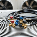 A person uses a wrench to tighten or adjust a metal fitting on an air conditioning unit.