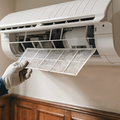 A dusty white wall air vent with a visible buildup of lint and debris, positioned near a floor and baseboard.