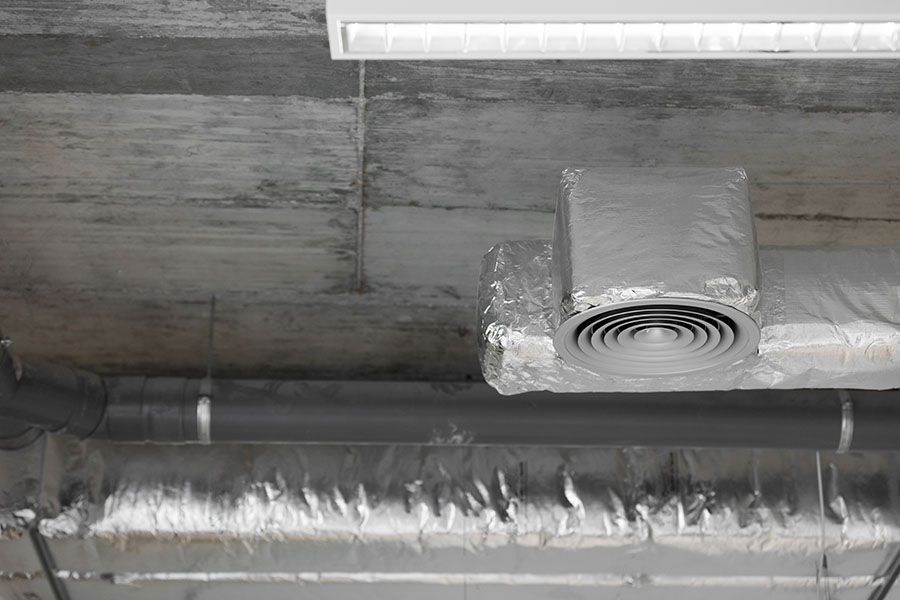 An industrial HVAC unit with two pleated filters sits inside a utility closet with light-colored walls and carpet.