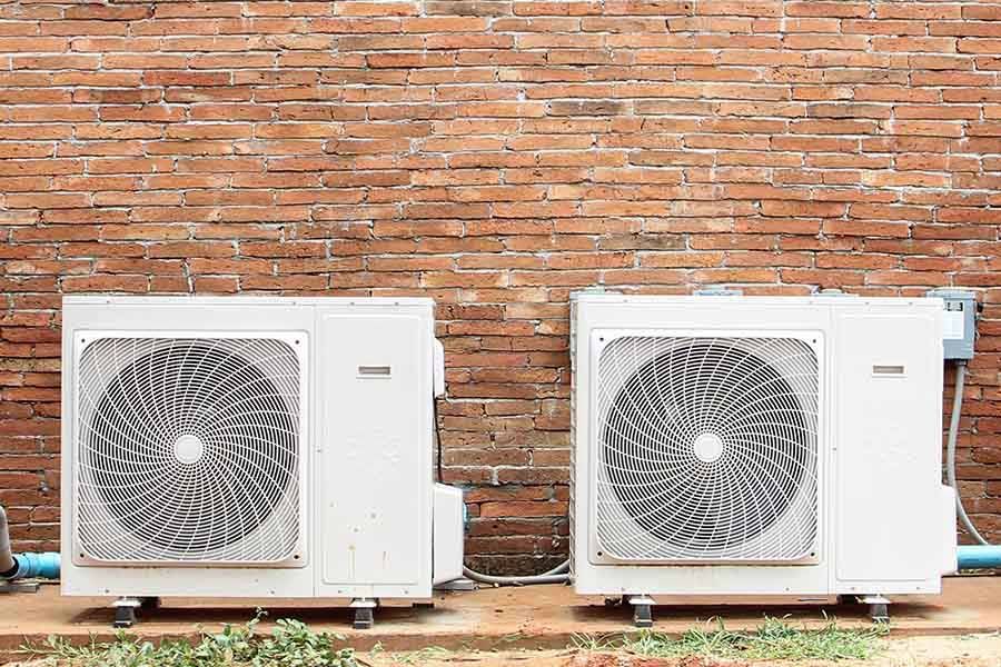An industrial HVAC unit with two pleated filters sits inside a utility closet with light-colored walls and carpet.