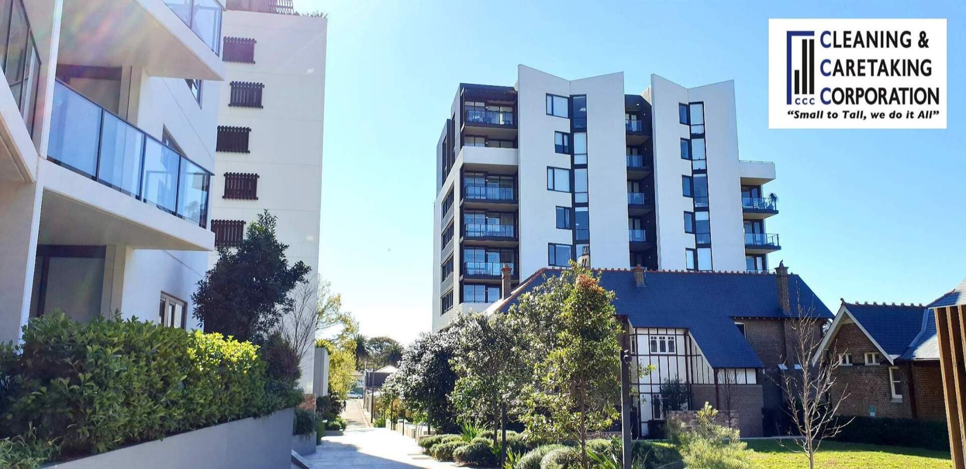 Modern apartment buildings with a landscaped courtyard and blue sky; Cleaning & Catering Corporation logo in corner