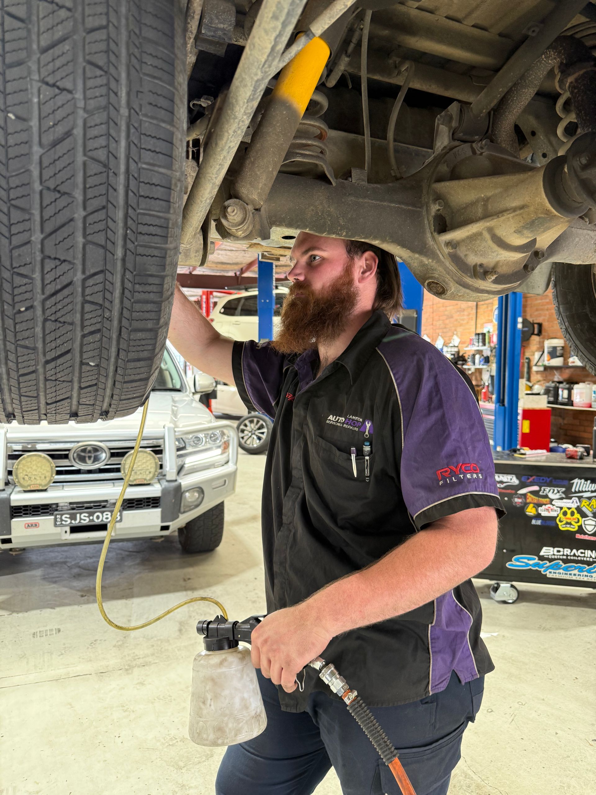 Jackson a qualified mechanic in Newcastle performing a wheel alignment in the workshop — AutoHop Lambton in Lambton, NSW