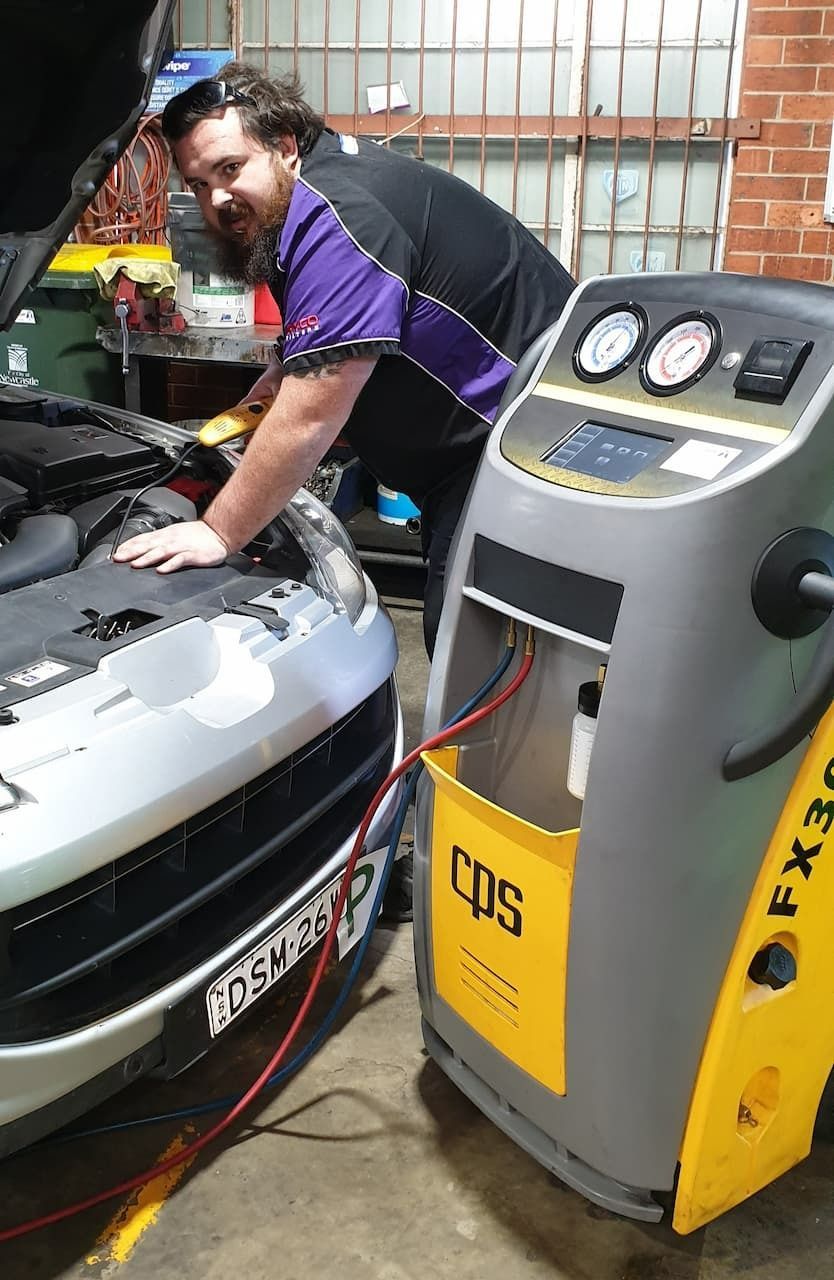 A Newcastle Mechanic Working on A Car Next to An A/C Service Machine in the workshop — AutoHop Lambton in Lambton, NSW