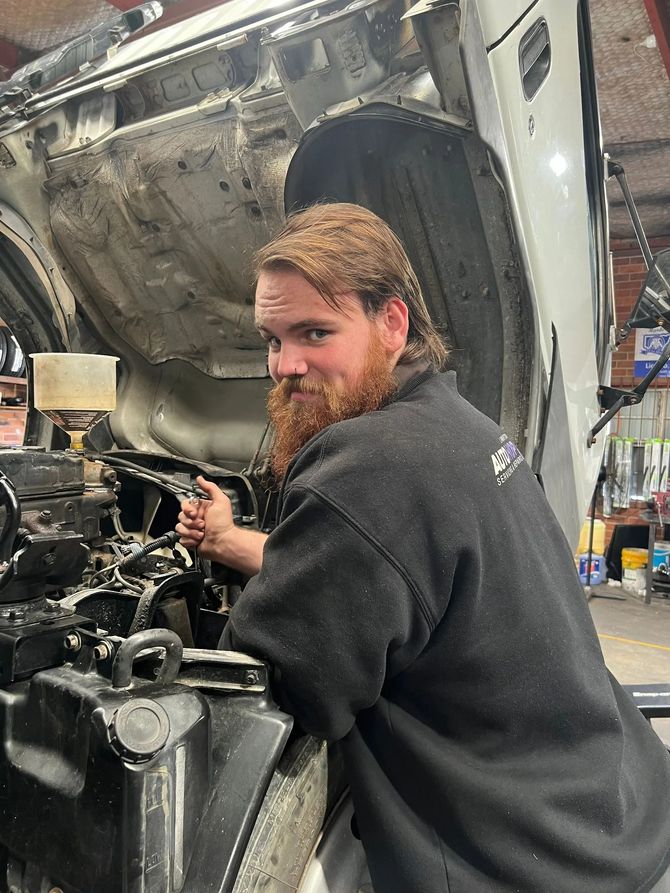 Mechanic in a black sweatshirt working on a car with its hood open in a garage — AutoHop Lambton in Lambton, NSW