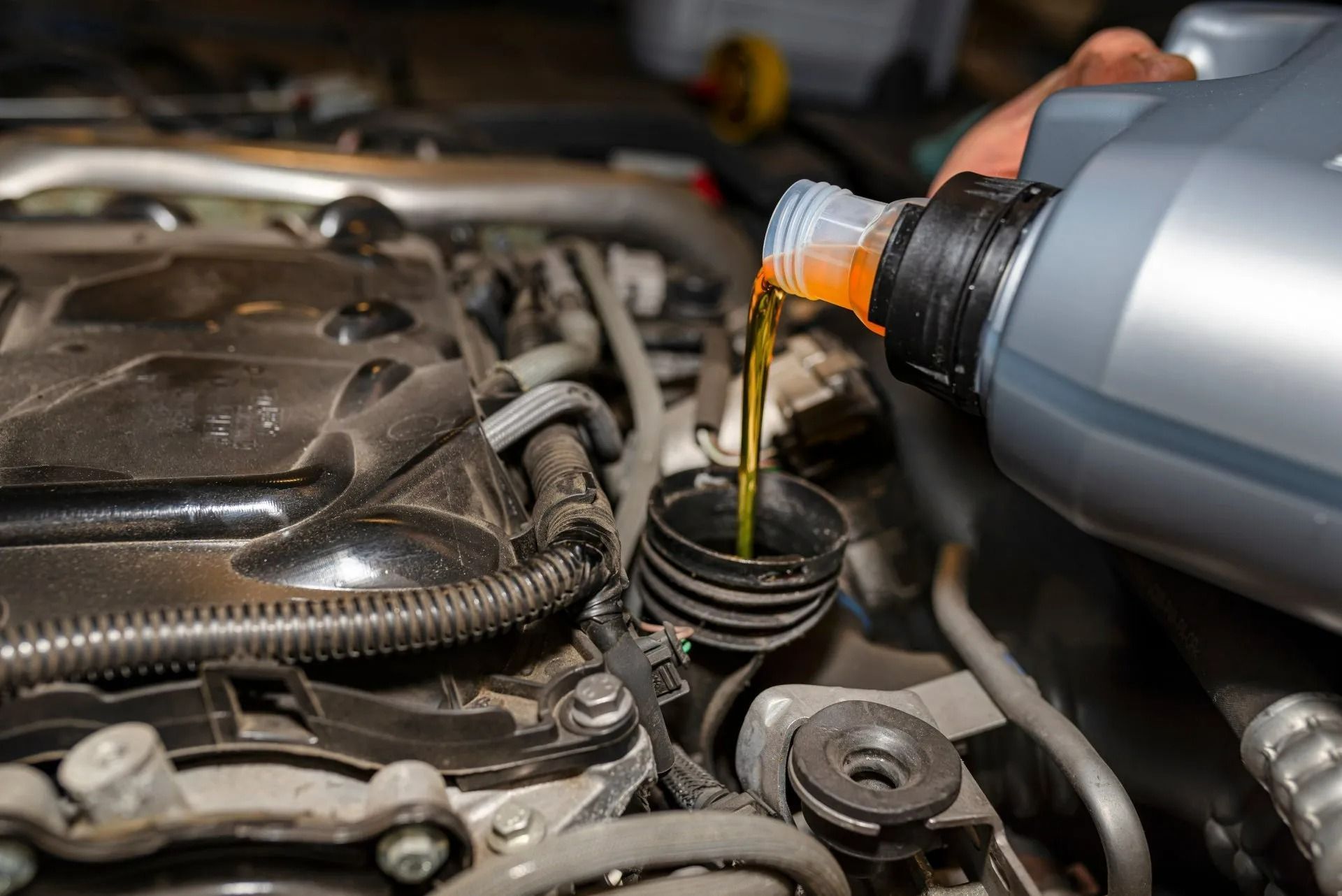 Pouring Oil Into a Car Engine, Orange Oil Flowing from A Grey Bottle — AutoHop Lambton in Lambton, NSW