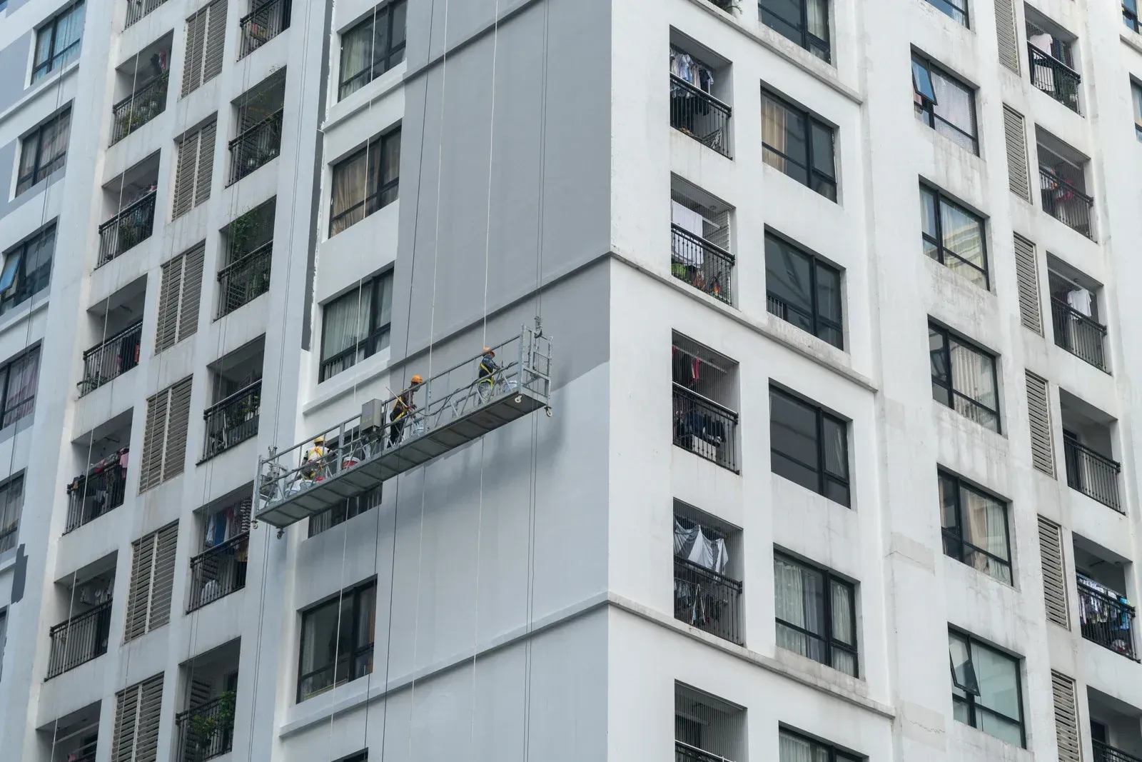A man is standing on a scaffolding on the side of a tall building.