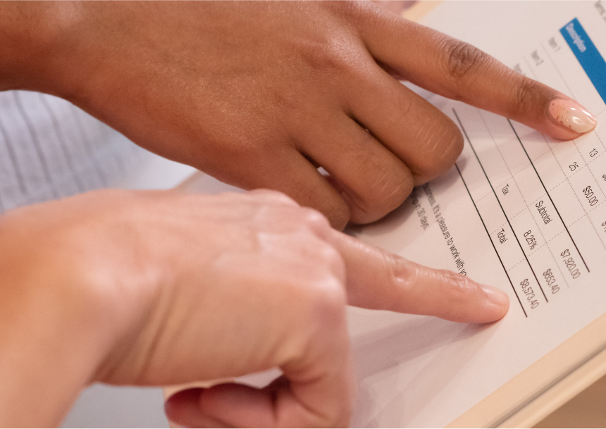 Two hands point at a piece of paper with numbers.