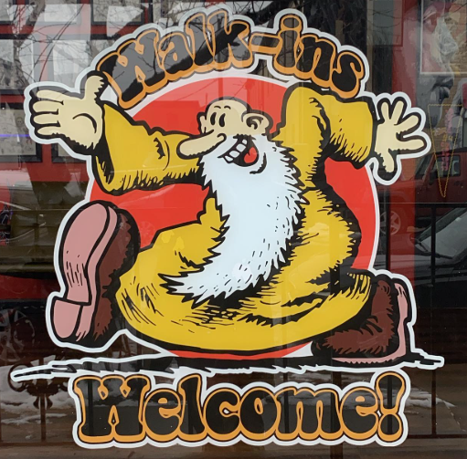 Walk-ins Welcome storefront sign featuring a cartoon character inspired by Mr. Natural at Classic Tattoo.