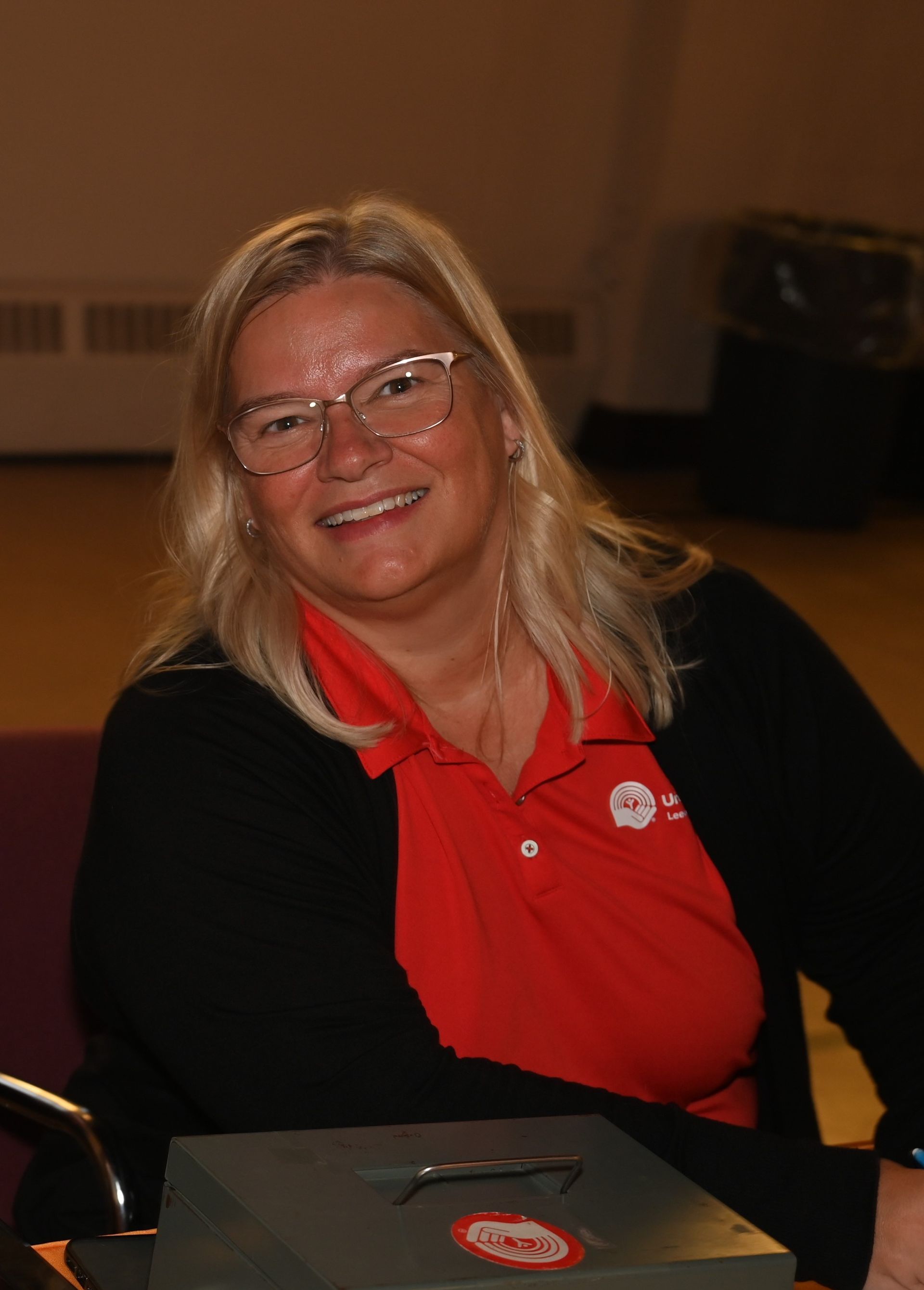 A woman wearing glasses and a red shirt is smiling for the camera.