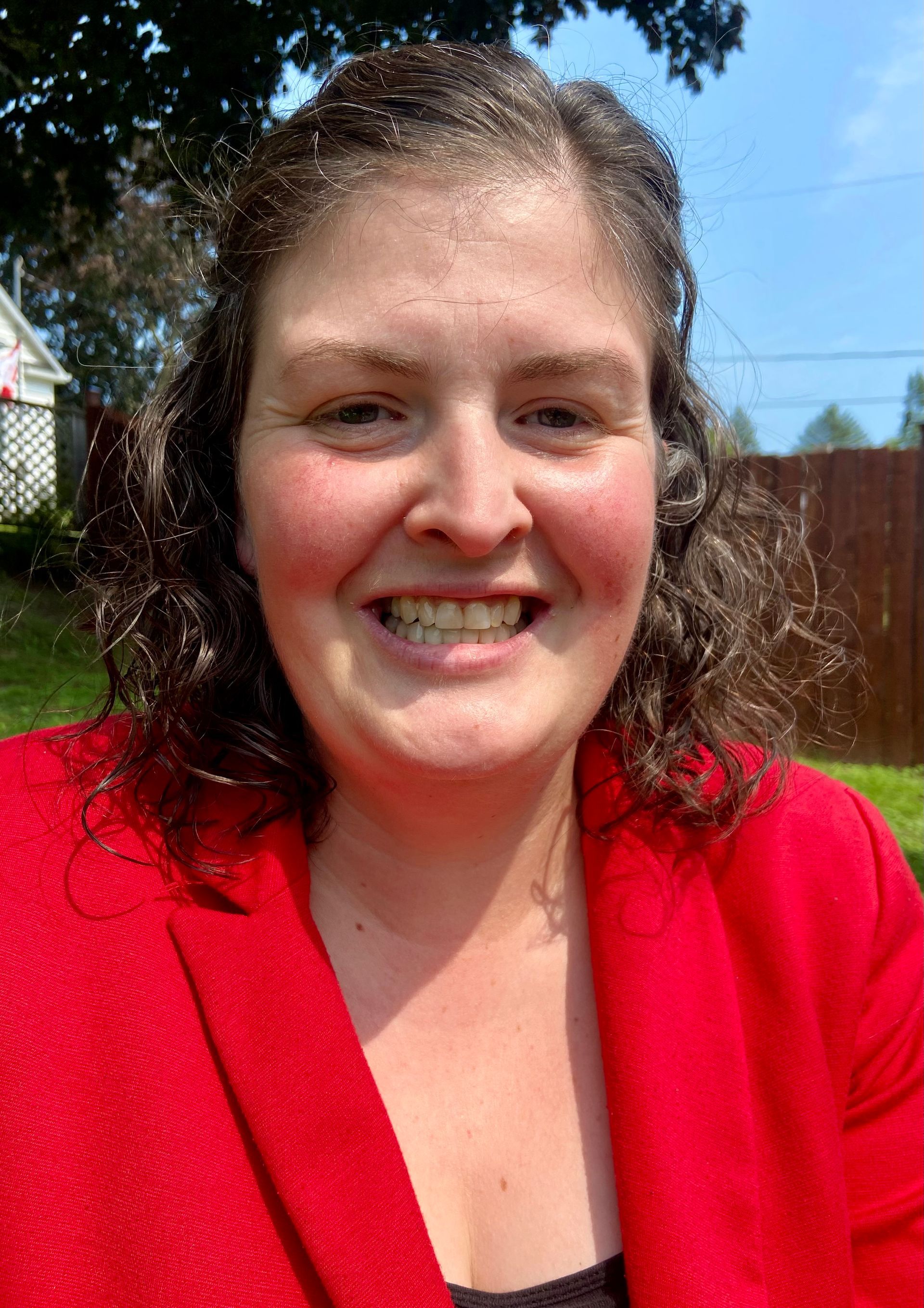 A woman in a red jacket is smiling for the camera.