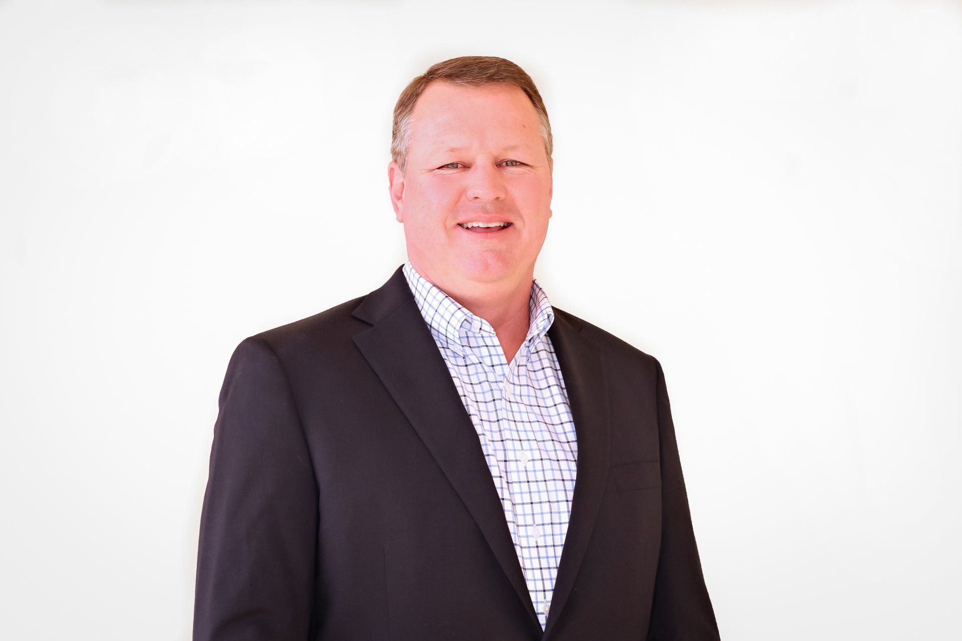 a man in a suit and plaid shirt is smiling for the camera