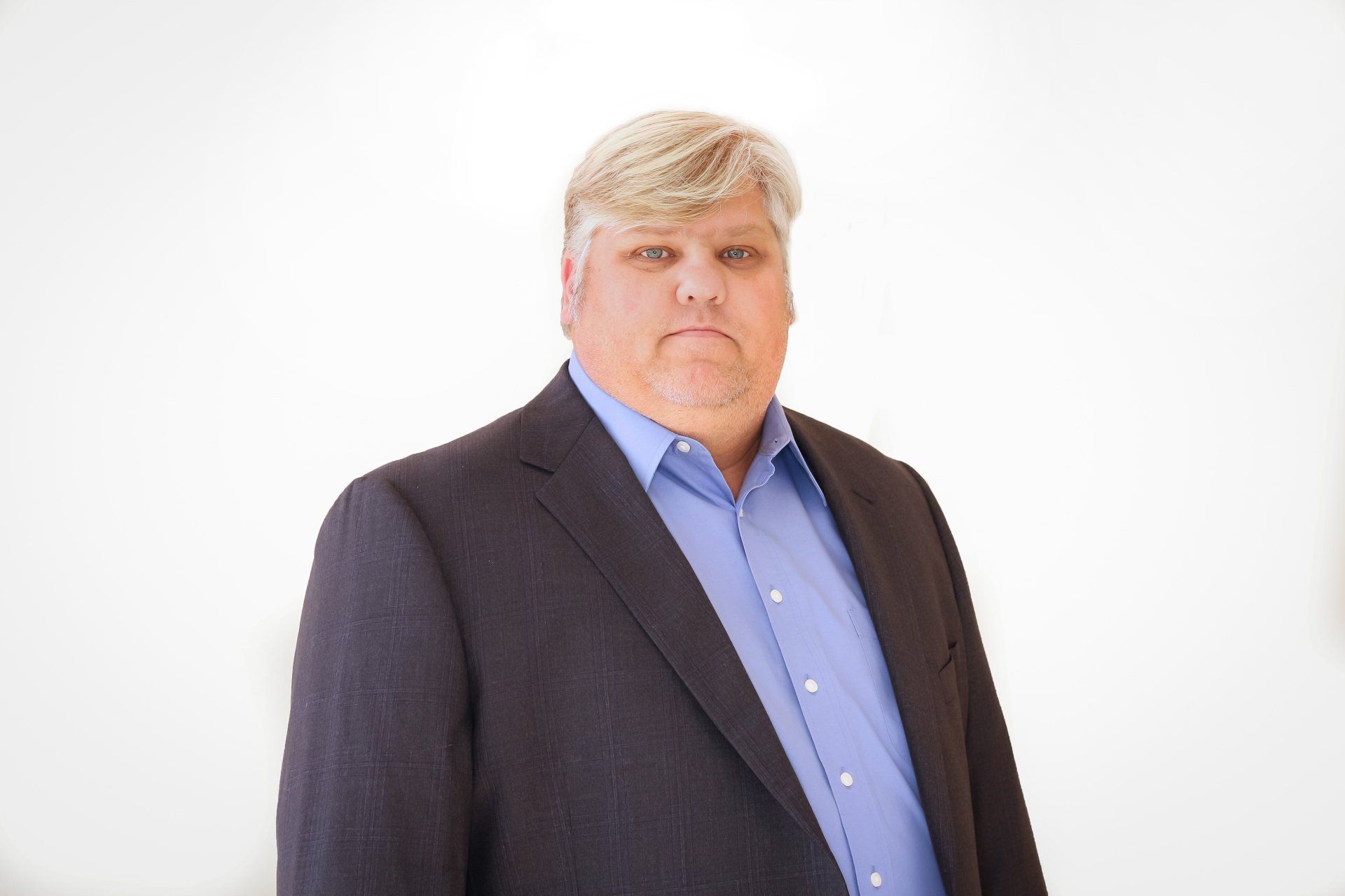 a man in a suit and blue shirt is standing in front of a white background