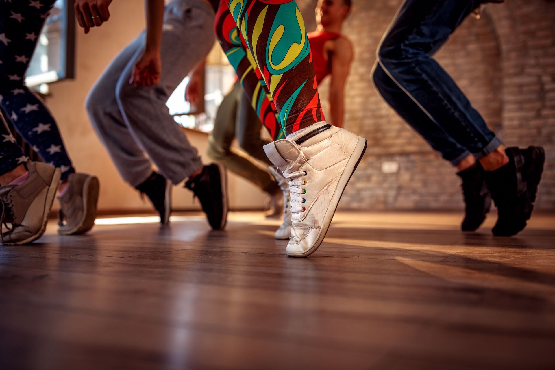 Close-up of white high-top sneakers moving on a wooden floor in studio dance classes.