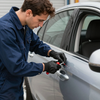 Person in blue work clothes using a tool to unlock a gray car door