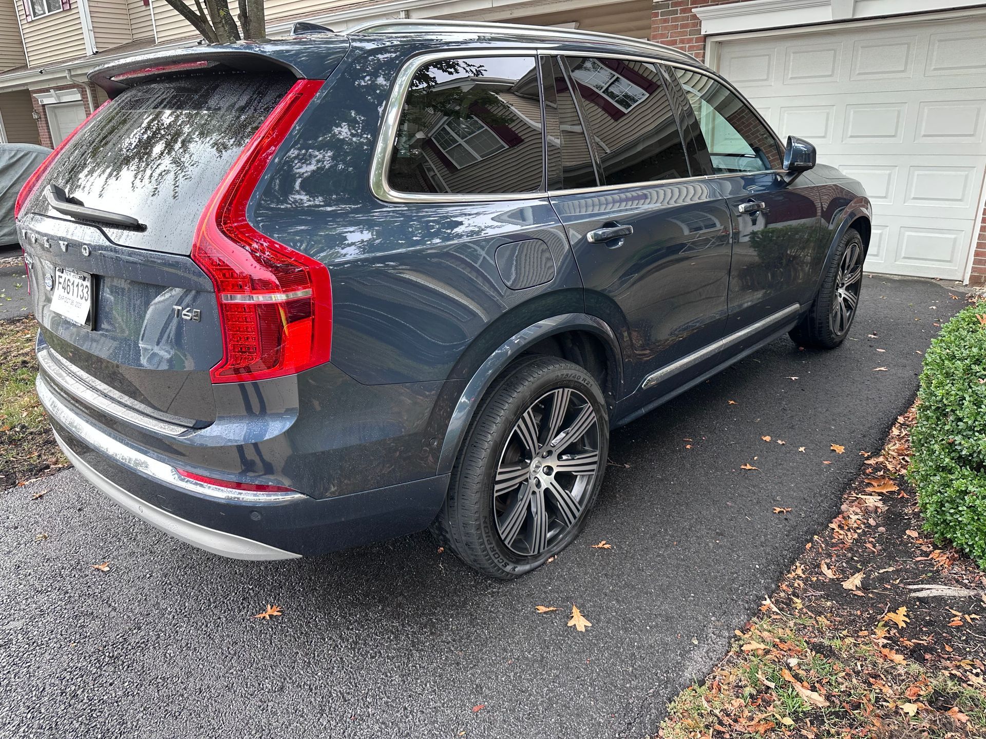 Gray SUV parked in a driveway beside a garage, viewed from the rear side