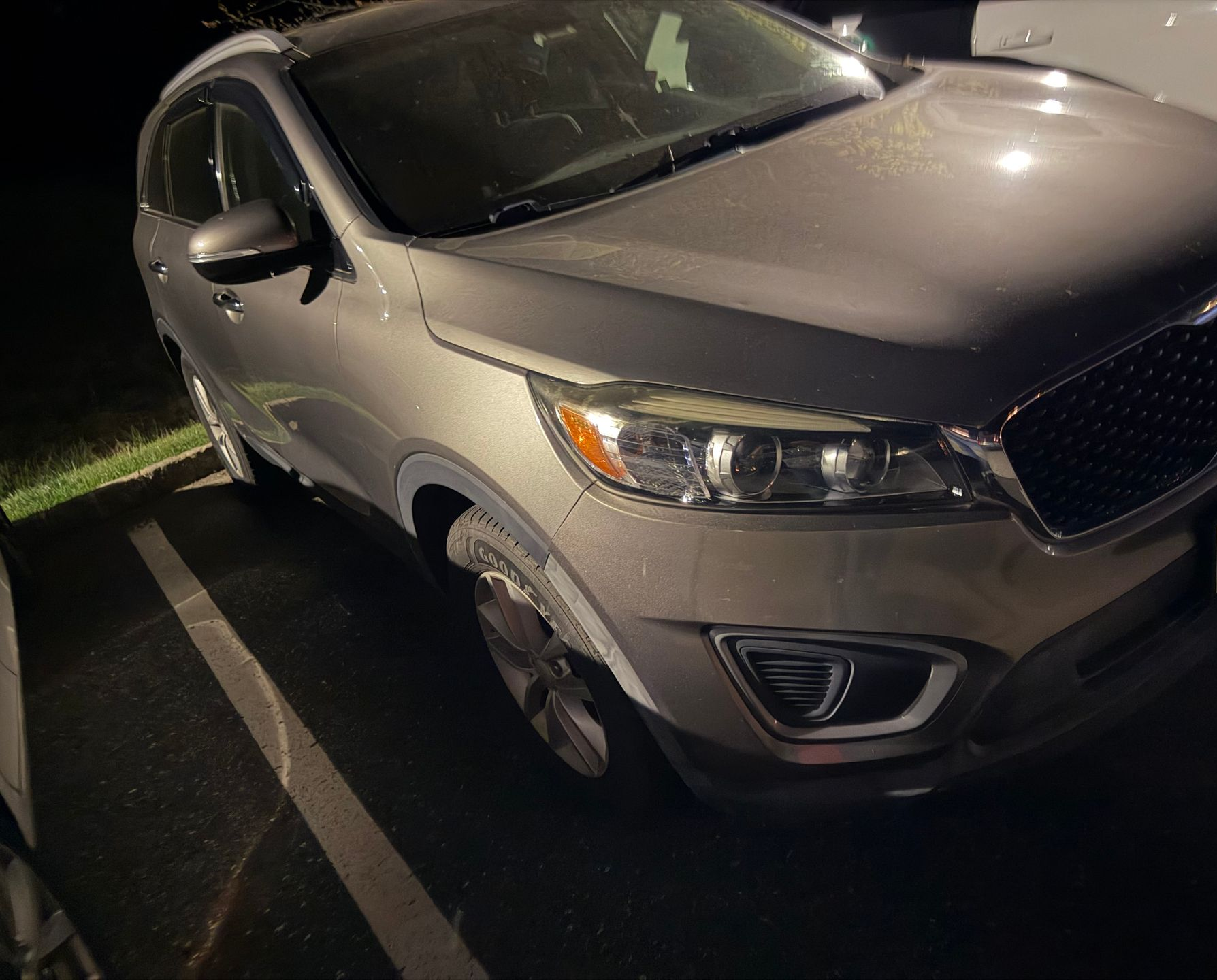 Gray SUV parked in a dark parking lot at night, front angled toward the camera.