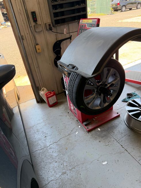 Large fan or wheel under a metal hood in a workshop, with tools and a red base nearby.
