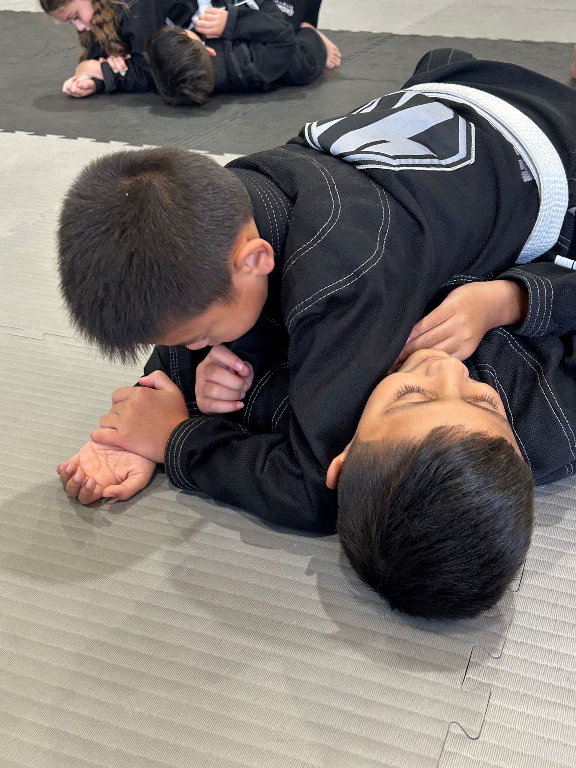 Two people practicing grappling on a mat during martial arts training at 4Korners Jiu-Jitsu in Princeton, TX