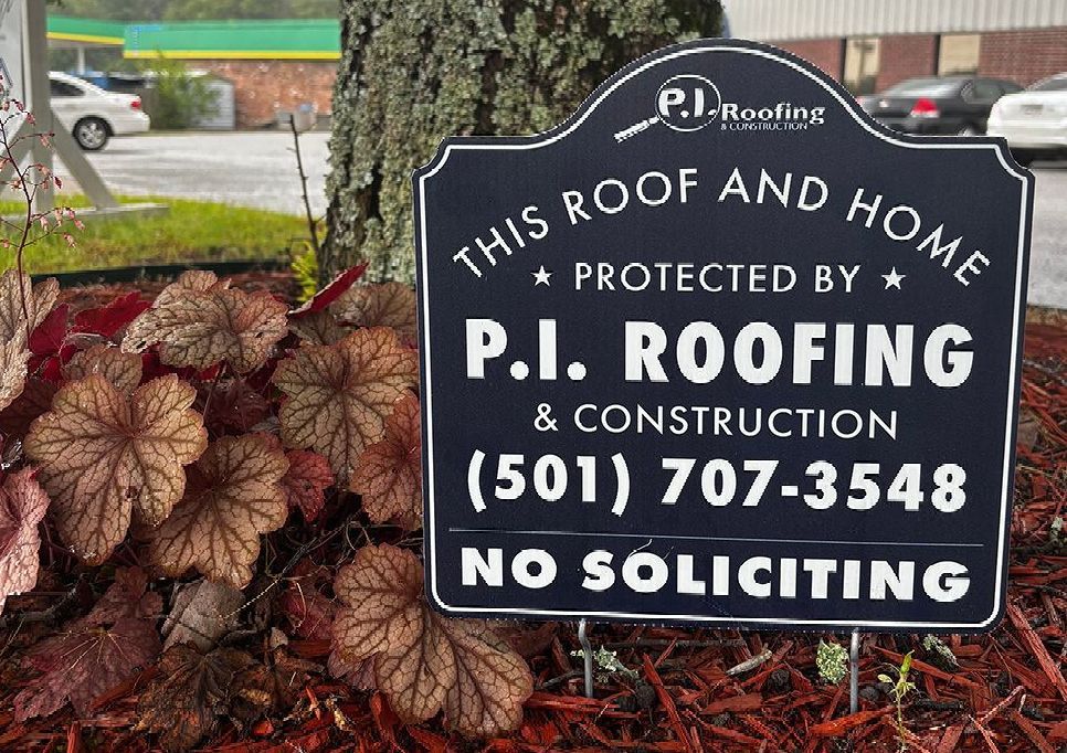 Black lawn sign for P.I. Roofing & Construction with a phone number and