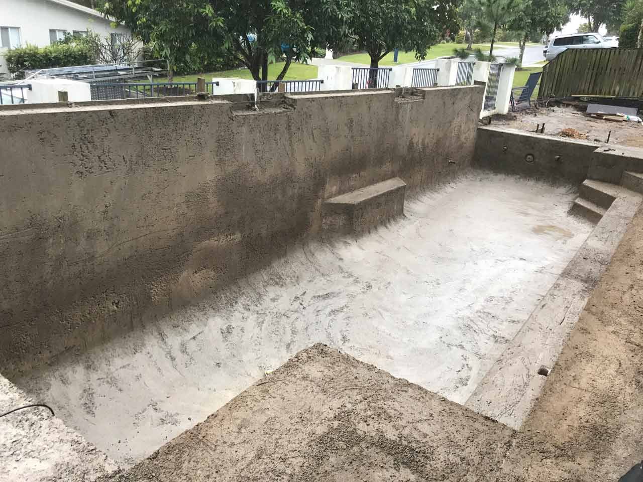 Empty concrete swimming pool under construction outdoors.