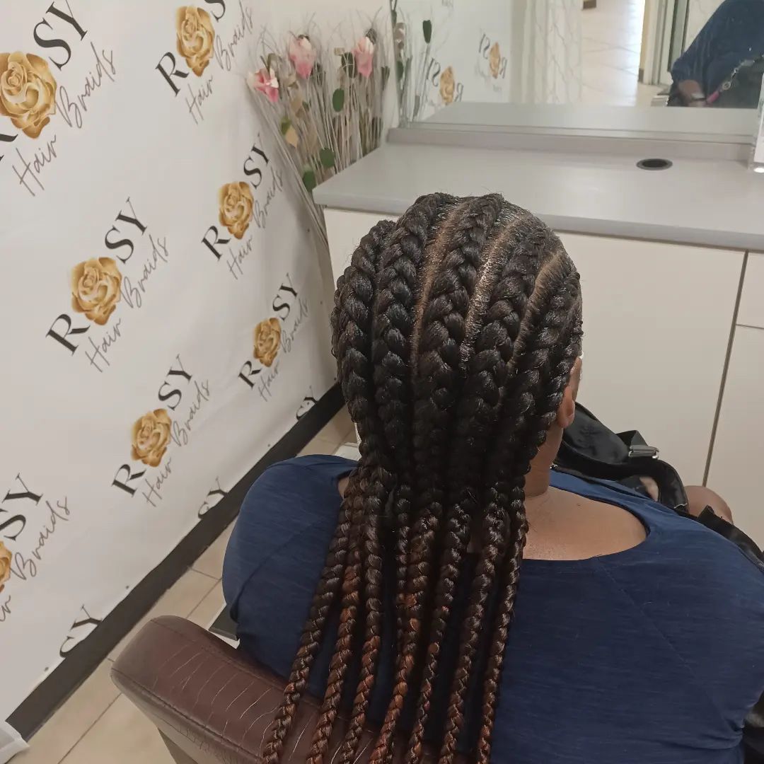 A woman with braids in her hair is wearing a white shirt