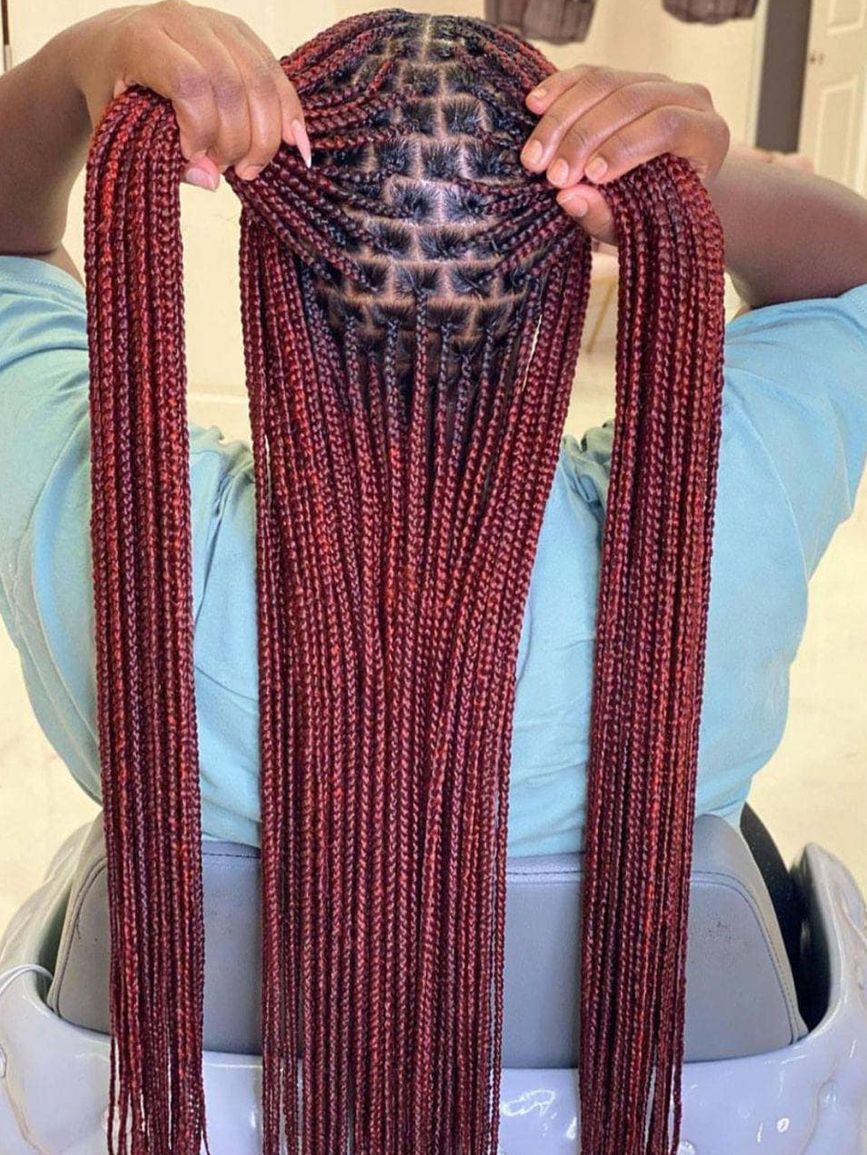 A woman with braids is wearing a denim jacket.