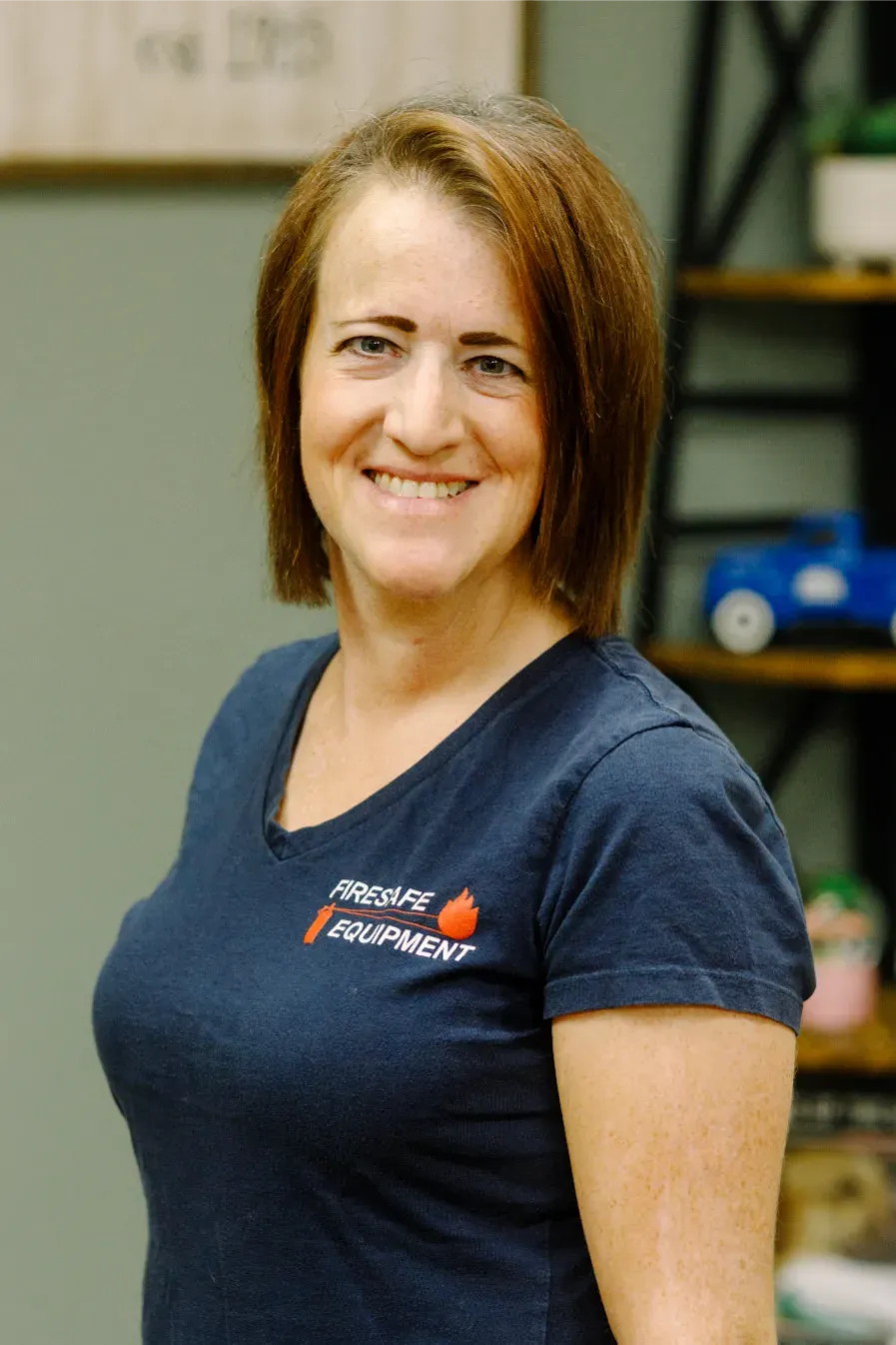 A woman in a blue shirt is smiling for the camera.