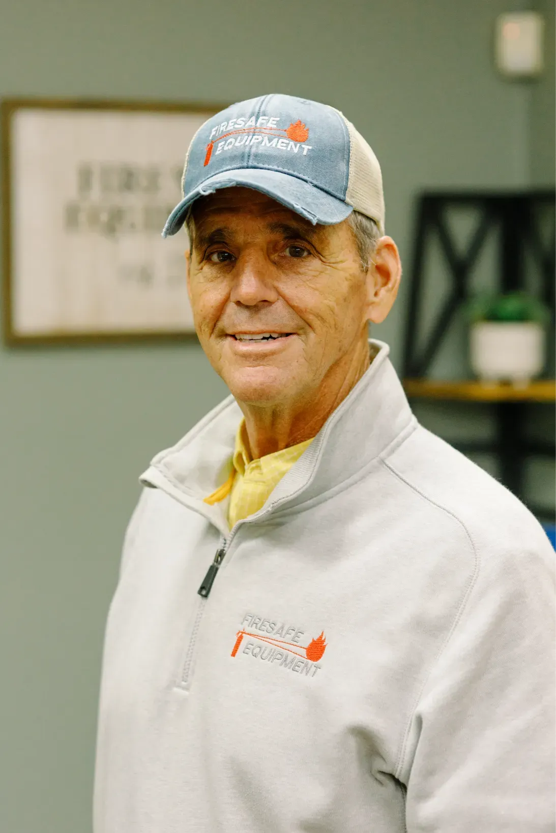 A man wearing a hat and a jacket is smiling for the camera.