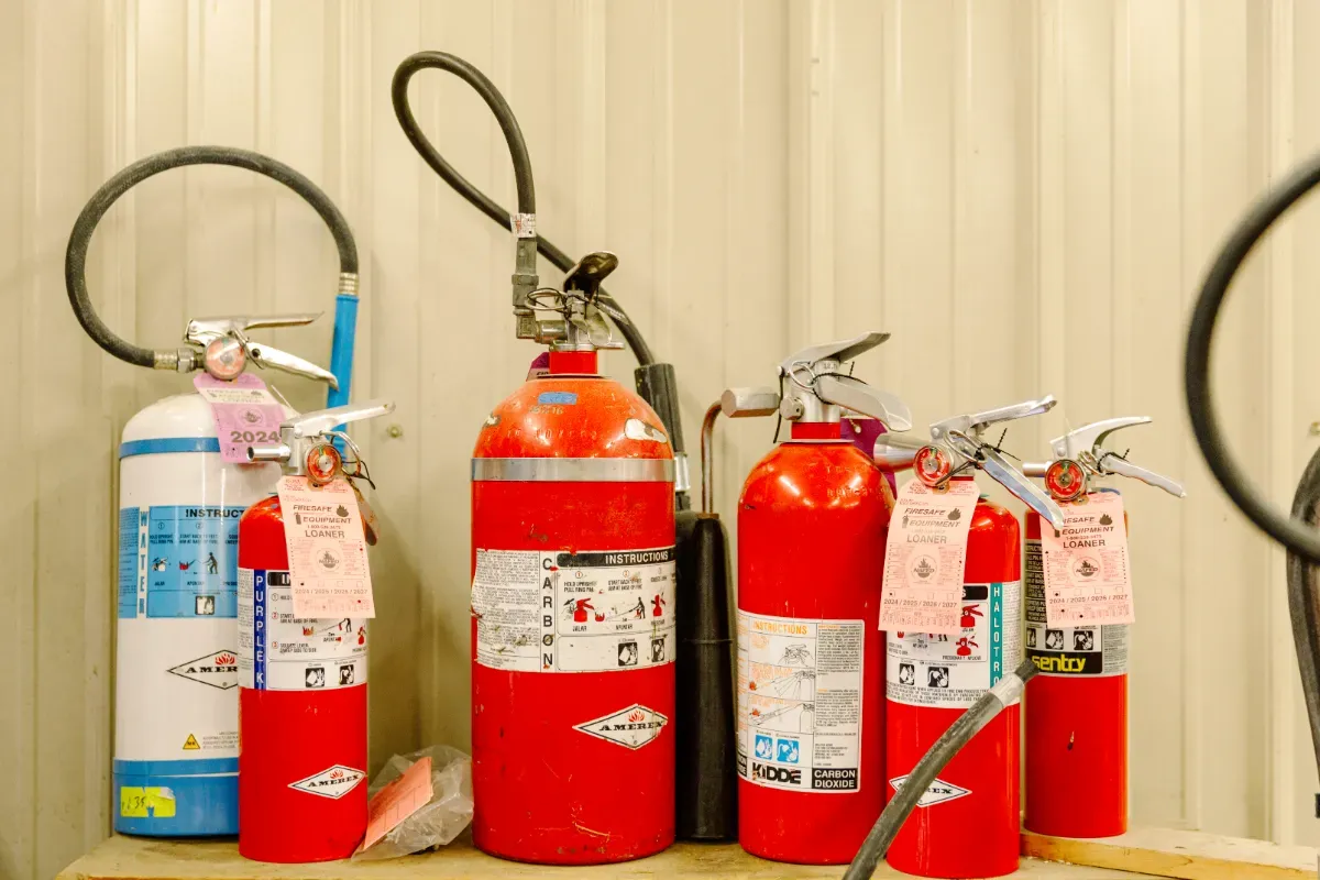 A row of fire extinguishers sitting on top of a wooden table.