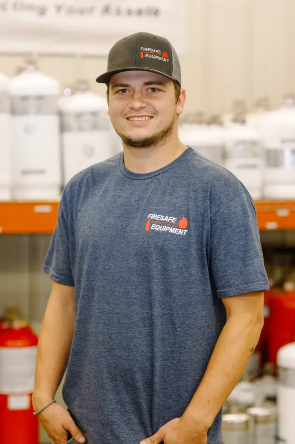 A man wearing a hat and a t-shirt is standing in front of a shelf.
