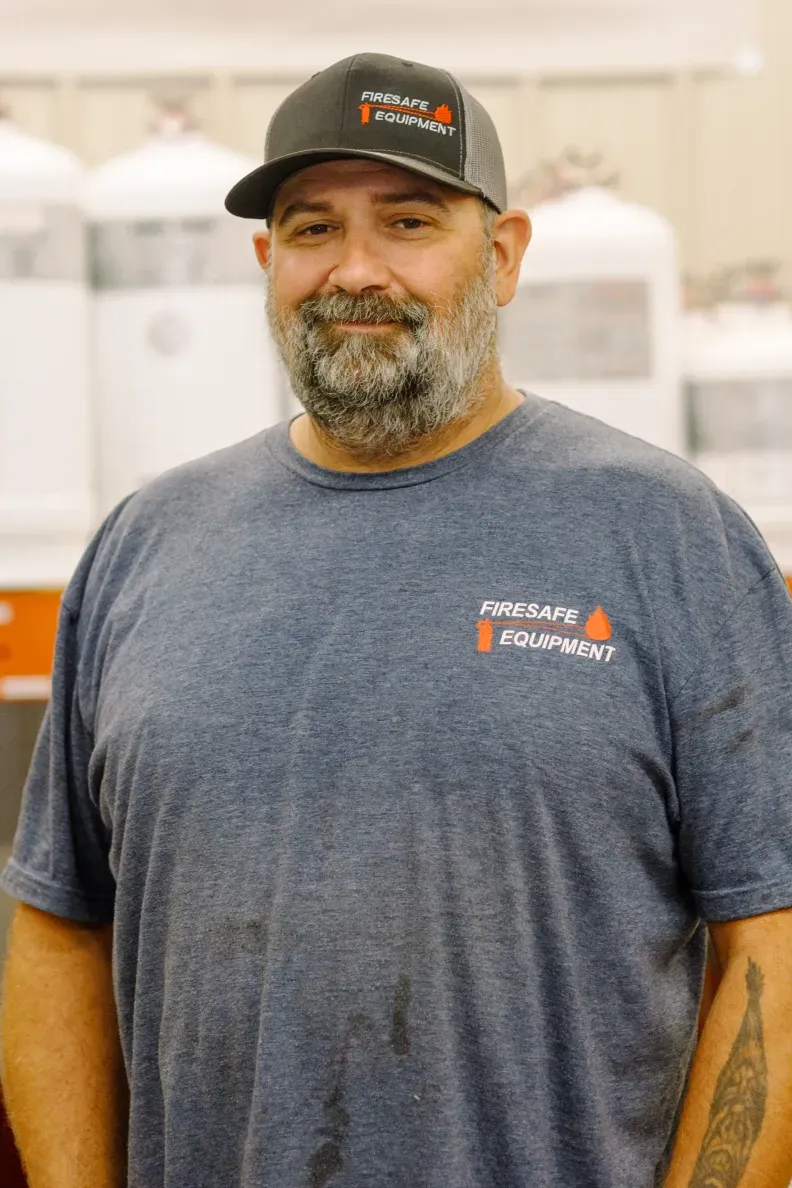 A man with a beard is wearing a hat and a blue shirt.
