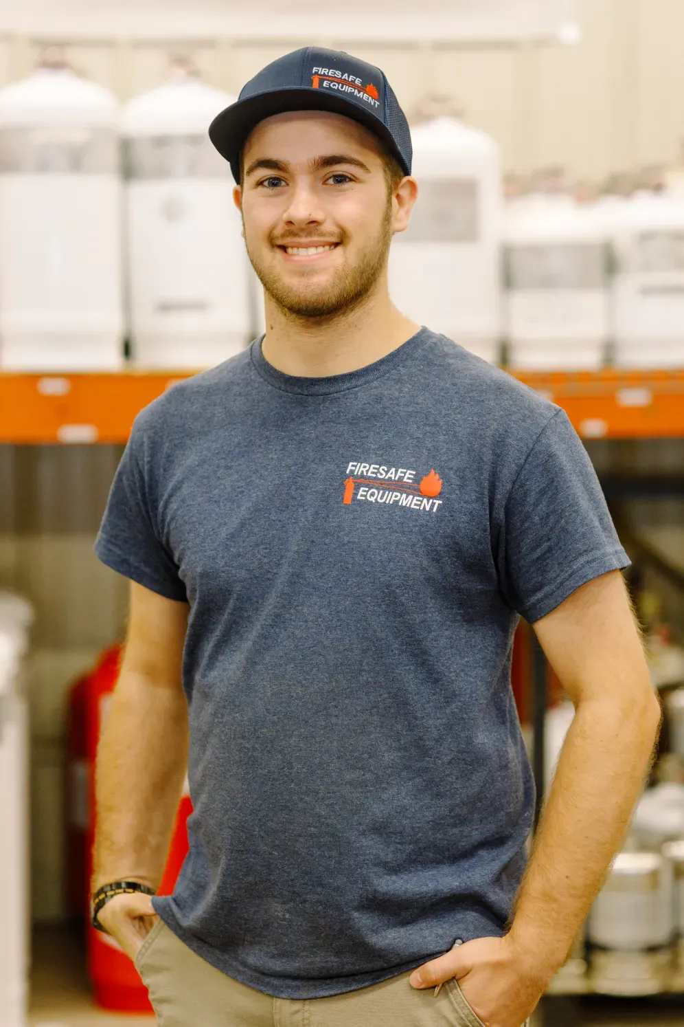A man wearing a hat and a t-shirt is standing in front of a shelf.