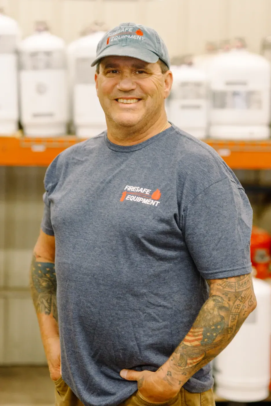 A man wearing a hat and a blue t-shirt is standing in front of a shelf.