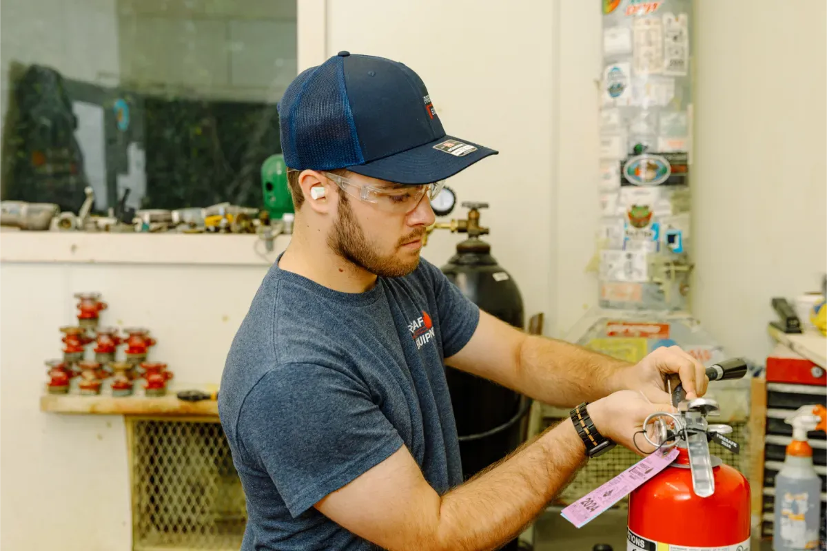 A man is working on a fire extinguisher in a garage.