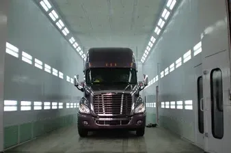 A purple semi truck is parked in a paint booth.