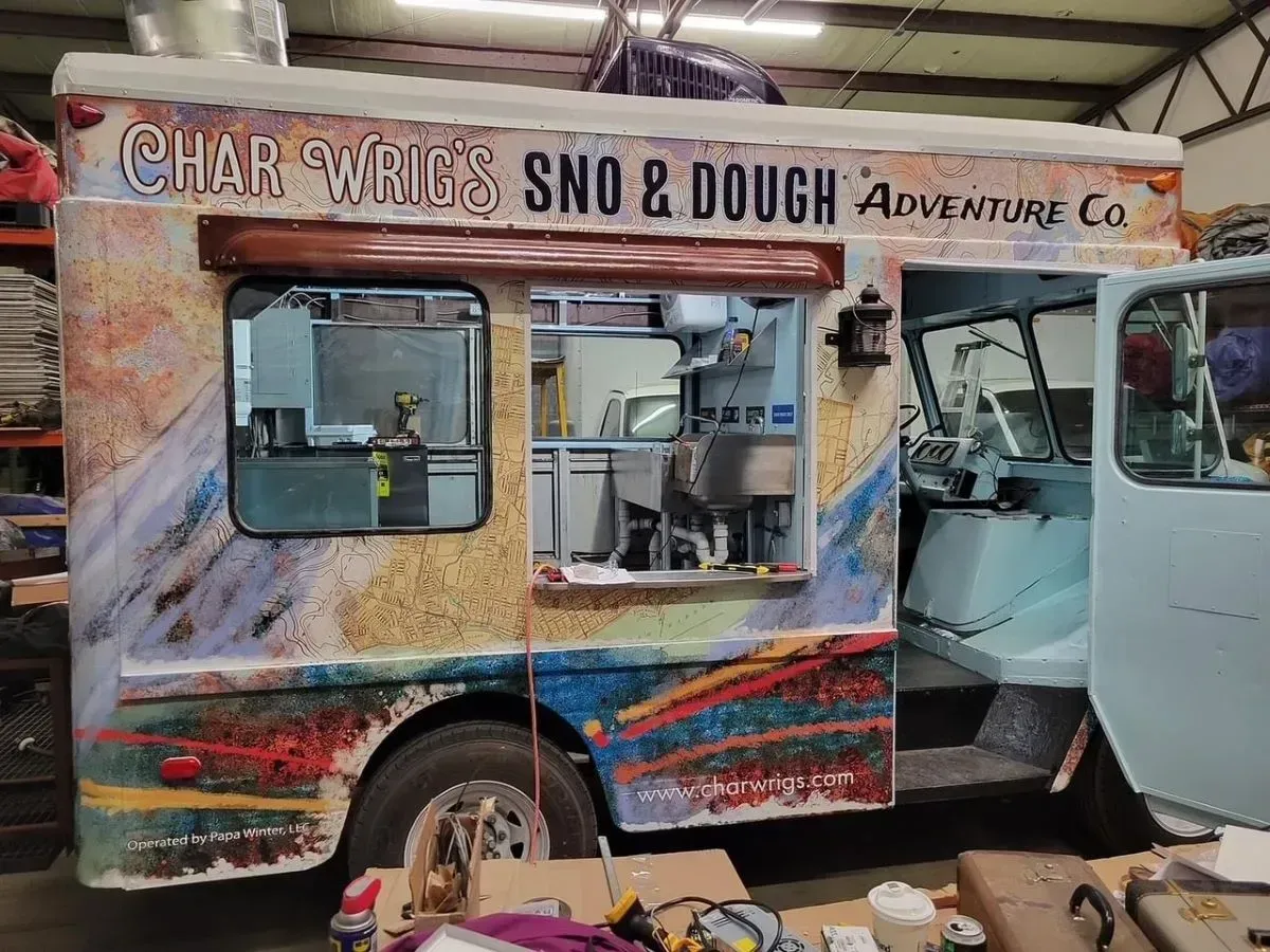 A food truck is parked in a garage with the door open.