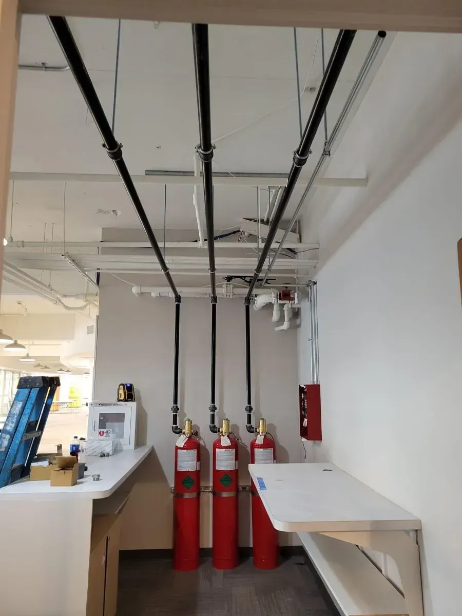 A room with red fire extinguishers and pipes hanging from the ceiling